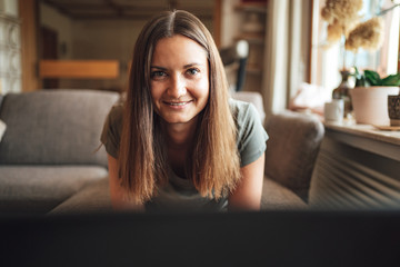 Portrait of attractive young woman with long brown hair smiling at home