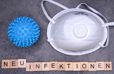 Holzklötzchen mit den Buchstaben: NEUINFEKTION sowie Virus und Mund-Nase-Schutz