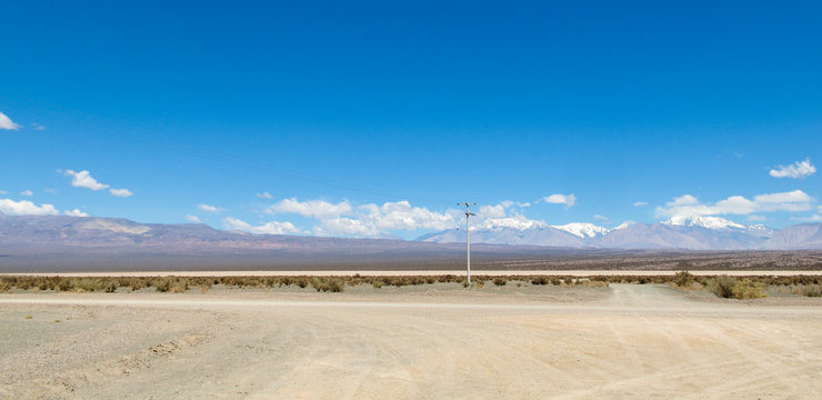 Drought land on the Pampa of El Leoncito with the Andean mountains against a clear blue sky. Dry soil texture