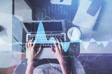 Double exposure of woman hands working on computer and forex chart hologram drawing. Top View. Financial analysis concept.