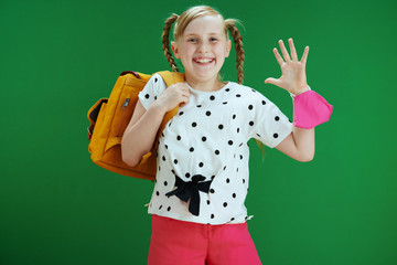 smiling modern child jumping and handwaving isolated on green