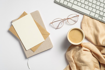 Elegant feminine workspace with pc keyboard, glasses, beige plaid, glasses, blank paper card,...