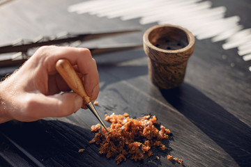 A person takes tobacco. The person is preparing a hookah. There is a table.