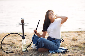 A woman has brunette hair. She is young. The lady is smoking.