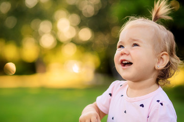 little girl blows bubbles in the park on green grass