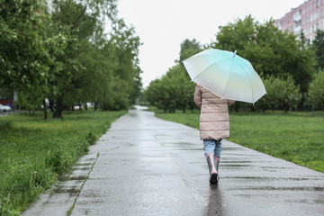 child walks under an umbrella in the rain