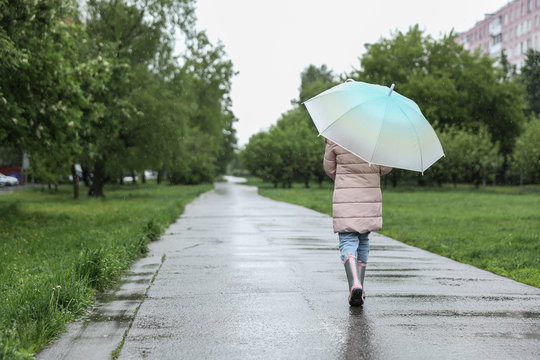 Child Walks Under An Umbrella In The Rain