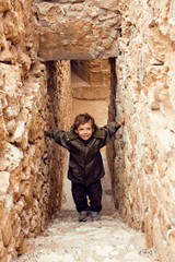 Obraz na płótnie Canvas little cute real boy among ancient ruins, greek vacations