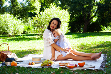 young pretty pregnant brunette woman having fun with her daughter on picnic on green grass in park, lifestyle people concept