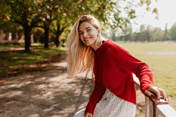 Smiling blonde woman laughing on the street cheerfully. Lovely young lady feeling happy in the autumn park.