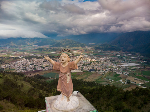 Aerial drone view of Jesus baby statue (Divino Ni&ntilde;o), mountains and valley with city Constanza, Dominican Republic 