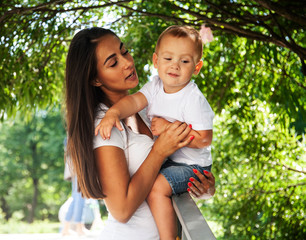 Fototapeta premium young pretty brunette mother with little cute boy walking in park happy smiling, lifestyle people concept
