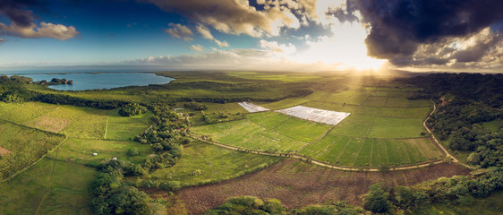 Aerial drone view of valley with rice fields and Atlantic Ocean at sunset in Sabana de la Mar,...