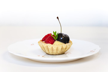 singular fruit tartlet on a floral plate on a white surface