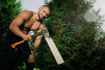 young man with a hatchet job green garden. Caucasian appearance