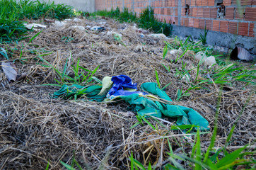 torn, dirty and rolled-up brazil flag thrown through trash on empty ground