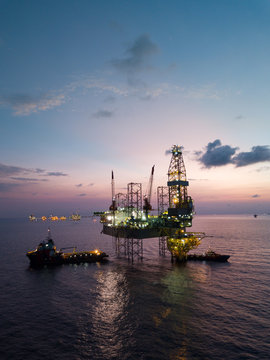 Aerial view offshore jack up rig at the offshore location during sunset with supply vessels and CPP