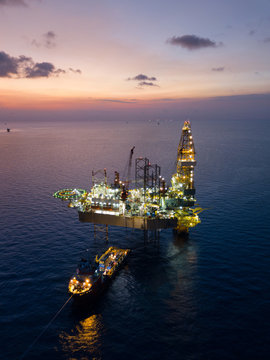 Aerial view offshore jack up rig at the offshore location during sunset with supply vessels and CPP