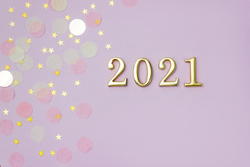 Golden number 2021 on pink background decorated with pastel starry confetti. New Year celebration concept.
