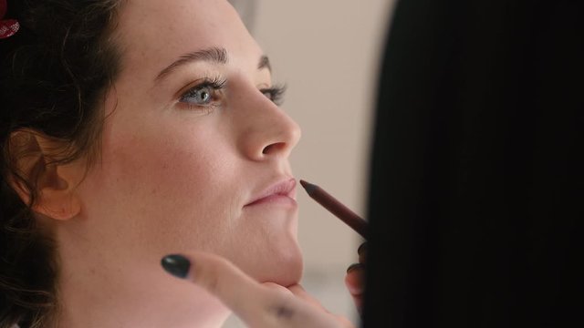 Getting Ready for Wedding: Attractive young Bride has lip liner applied