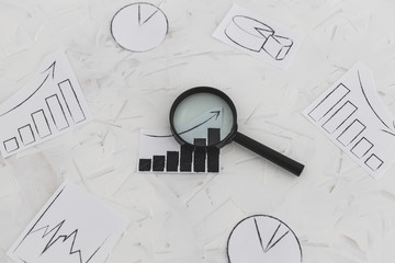 business analysis and statistics, desk with mixed graphs and charts with magnifying glass on it
