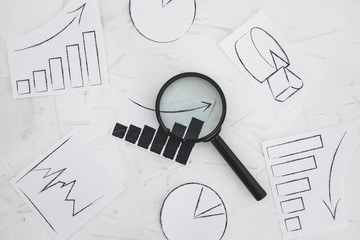 business analysis and statistics, desk with mixed graphs and charts with magnifying glass on it