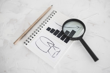business analysis and statistics, desk with mixed graphs and charts on notebook with magnifying...