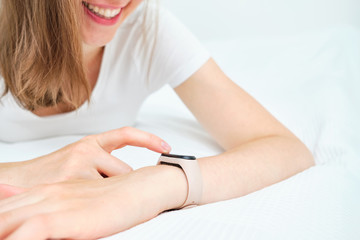 Obraz na płótnie Canvas Girl smiles and uses a smart watch