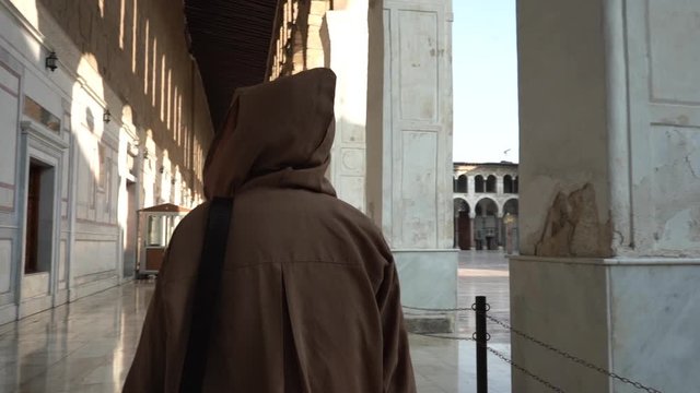 Person in Monk Tunic WIth Hoodie Walking in a Exterior of Umayyad Grand Mosque. Damascus Syria. Slow Motion