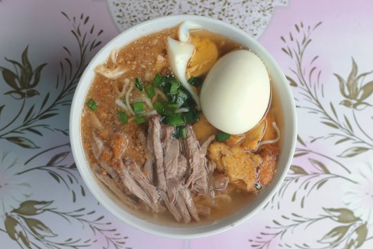 Batchoy or batsoy, a noodle soup in Philippines made with pork offal, crushed pork cracklings, chicken stock, beef loin and round noodles. Shallow depth-of-field. 