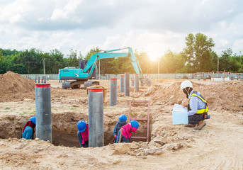 Supervisor surveyer engineer control workers working and checking level excavation depth of foundation at construction site.