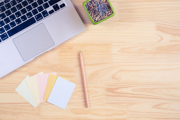 Top view of laptop, papers, and pencil on wooden background