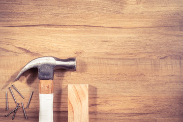 Top view of hammer, nails, and timber on wooden background