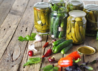 Wooden background with cucumbers.The process of preserving cucumbers in glass jars under lids for...