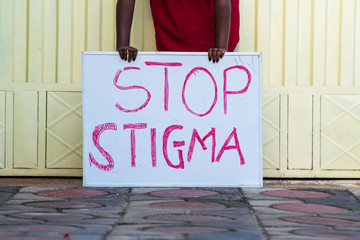 Black person holding a sign with text "Stop Stigma"