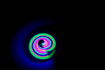 Long exposure photograph of a light spinning top with black background.
