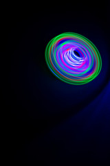 Long exposure photograph of a light spinning top with black background.