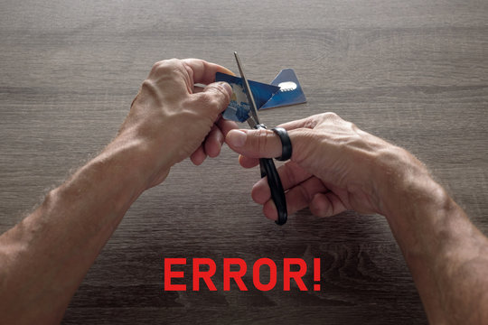 male hands with scissors cut the payment blue master card. concept of liquidation, destruction of deactivation, decommissioning with the inscription error.
