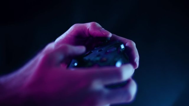 Playing video games in a darkened room with a black background close up on a controller buttons playing slowly blue lens flare