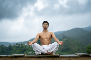 Naklejka na ściany i meble a man practicing meditation and zen energy yoga in mountains.Man doing fitness exercise sport outdoors in morning. Healthy lifestyle concept