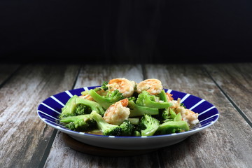 Traditional fried and stirred cutting fresh broccoli with fresh peeled shrimp seasoning with soy sauce and pepper on the plate. Famous appetizer menu in Asia restaurant. 