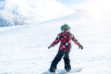 Fototapeta na wymiar Cute Boy Snowboarding Down the Slope