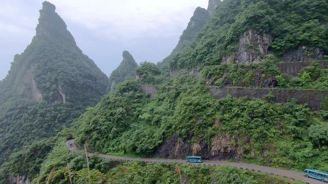 Small tourist buses taking dangerous sharp turns on the winding road of 99 turns to the top of the Tianmen Mountain, Zhangjiajie National Park, Hunan, China