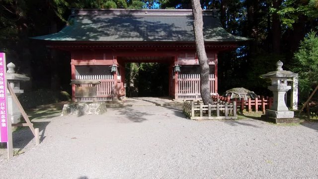 Walking towards the red entrace gate of the japanese Shrine of Mount Gassan, haguro shrine. Wide angle, dolly in
