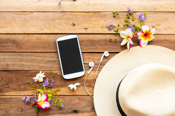 mobile phone ,earphone ,hat and flowers of lifestyle woman relax  arrangement flat lay style on background wooden