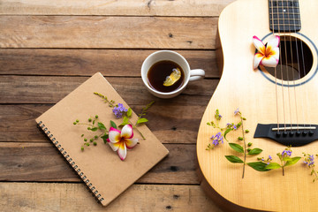 notebook planner ,hot coffee and guitar of lifestyle woman relax summer and flowers frangipani ,purple flowers arrangement flat lay style on background wooden 