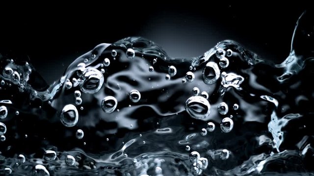Abstract splashing macro close up of water wave isolated on black background. Studio super slow motion shot with clear pure drinking water on cutout high key background splashing onto pov glass at hig