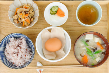 朝食の定食　ごはん　味噌汁　生卵　漬物　お茶　副菜