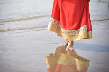 Obraz premium woman in red dress walking on beach