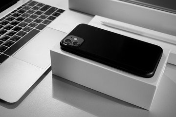 Organized desktop with mobile phone, laptop computer and stylus with boxes in black and white...